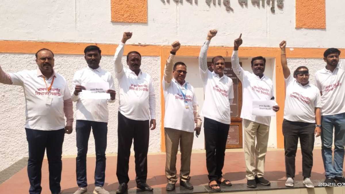 A group of men standing in front of a building with a sign in Marathi, raising their fists in solidarity. They are wearing white t-shirts with red Marathi text that reads "भ्रष्ट निवडणूक, निर्बंधित निवडणूक" (Corrupt Election, Restricted Election). Some of them hold papers with similar text. The group appears to be participating in a protest or awareness campaign against election corruption. The background features a white and orange wall, and the date on the bottom right corner of the image indicates it was taken on March 17, 2025.