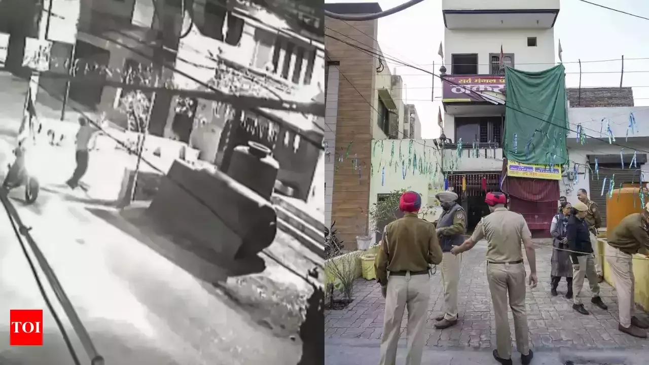 A composite image showing two contrasting scenes. On the left, a black-and-white CCTV footage still captures an explosion or attack on a street, with a person running away and a vehicle overturned. On the right, a color photograph shows Punjab Police officers investigating the scene of the incident outside a residential or commercial building, which is cordoned off with ropes. The officers wear khaki uniforms and red turbans, indicating their affiliation with Punjab law enforcement. The "TOI" (Times of India) logo is visible in the bottom left corner.