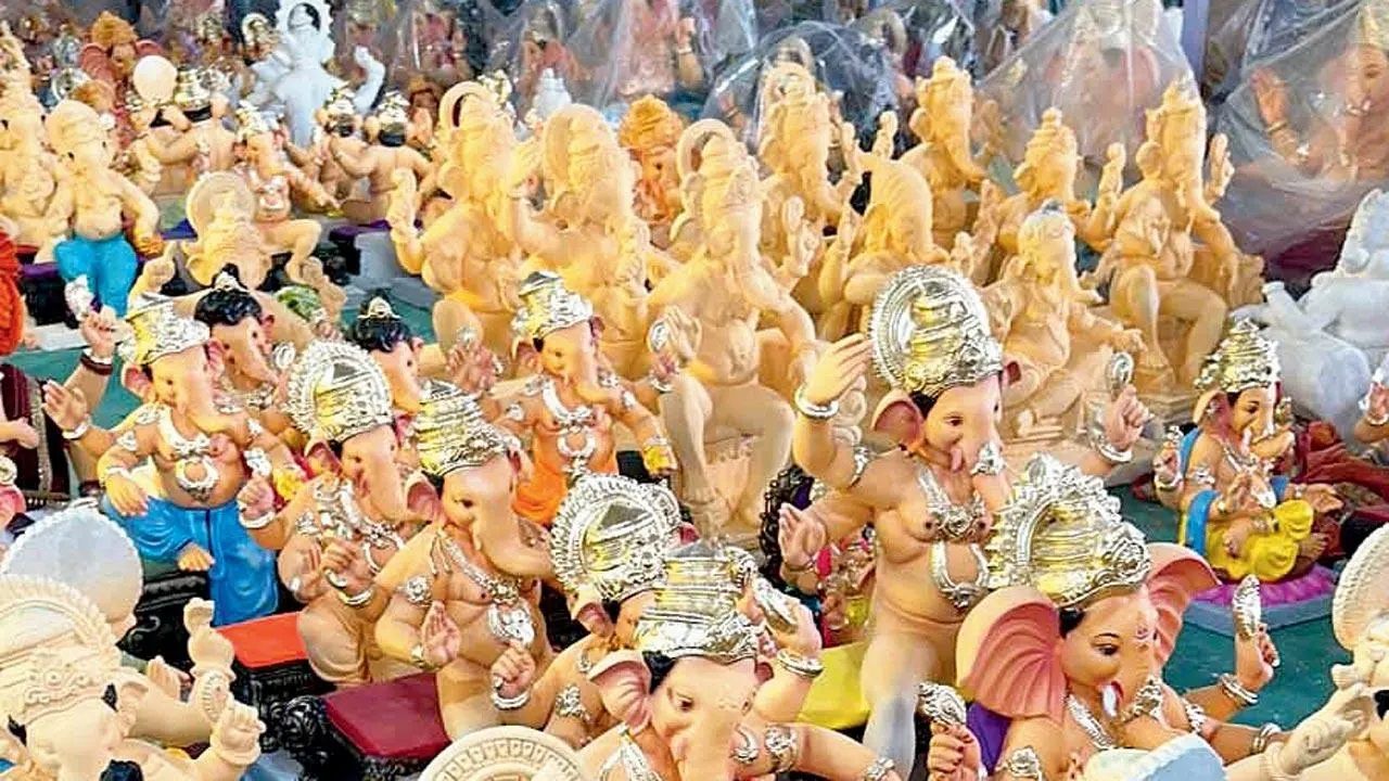 "A large collection of Lord Ganesha idols in various stages of completion at a workshop. Some idols are unpainted, while others are adorned with silver crowns and intricate jewelry. The idols are arranged closely, showcasing the craftsmanship involved in their creation before the Ganesh Chaturthi festival."