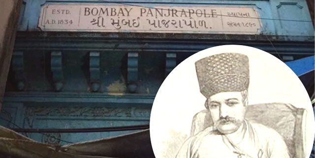  A photograph of the entrance to the historic Bombay Panjrapole, an animal shelter established in 1834 in Mumbai. The signage on the building is in English and Gujarati, indicating its long-standing presence. Inset is an old illustration of a man wearing a traditional Parsi hat, possibly associated with the institution's founders or benefactors. The image highlights the heritage and philanthropic legacy of animal welfare in colonial Bombay.